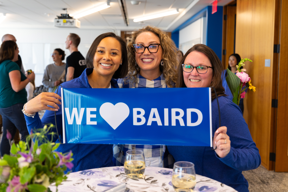 Three women holding a We Love RJF Pro sign while attending the RJF Pro Annual Meeting