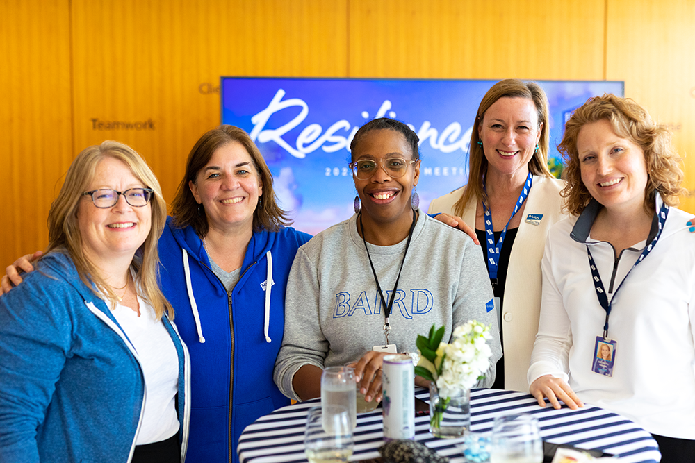 Group of five women standing together at a reception table wearing RJF Pro branded clothing.